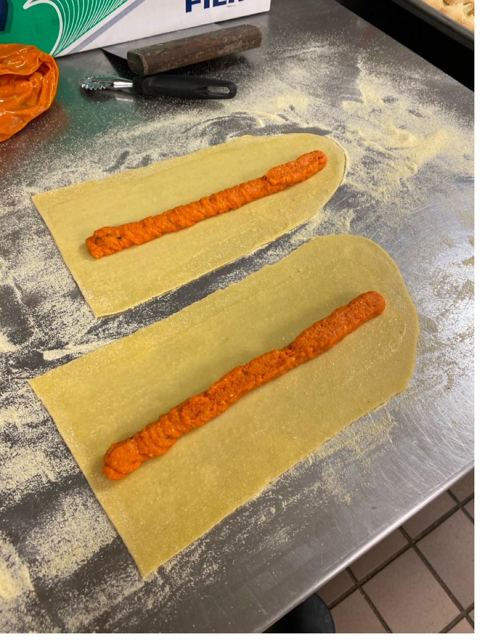 Butternut squash filling being piped onto fresh pasta sheets for ravioli