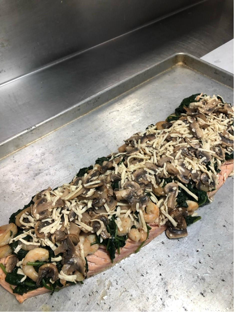 Salmon fillet topped with spinach, mushrooms, shrimp, and cheese before being wrapped in pastry