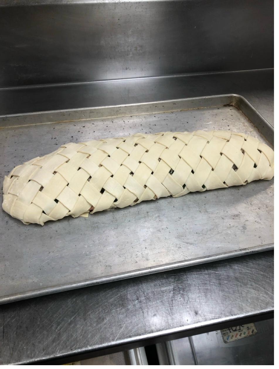 Salmon en croûte with intricate lattice-woven puff pastry ready for baking