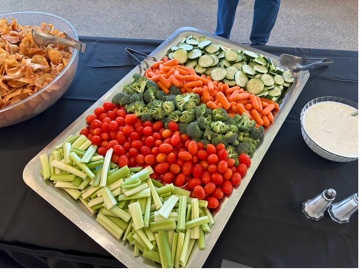Large fresh vegetable crudité platter with celery, tomatoes, broccoli, carrots, and cucumbers served with ranch dip