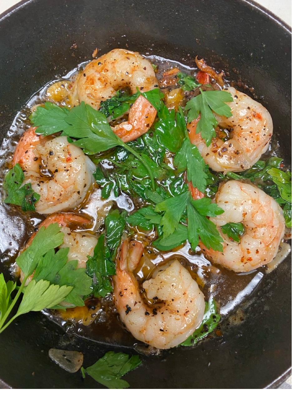 Sautéed shrimp scampi in garlic herb butter in cast iron skillet with fresh parsley